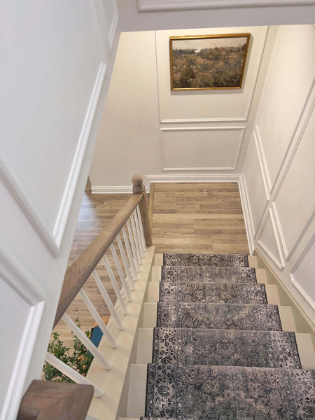 Looking down the steps of a staircase with a white oak stair railing.
