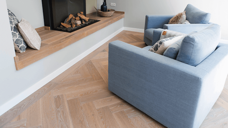 A classic herringbone wood floor with a light color floor finish on it.