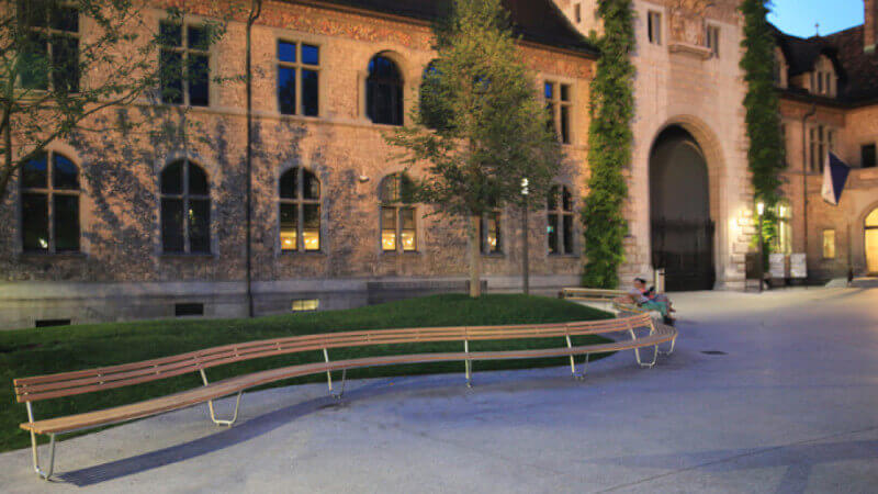 A long curving bench made from larch wood and finished with exterior wood oil.