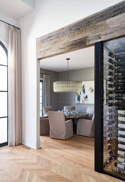 White oak chevron floors in a custom home next to a dining area and wine room.