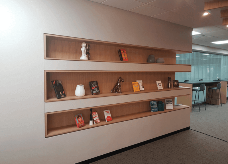 Recessed wood shelving in the wall of a shared office space.