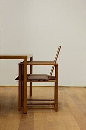 Side view of half a table and a chair on a hardwood floor.