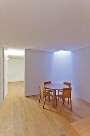 A room with white walls and a hardwood floor with only 1 table and 4 chairs in it.