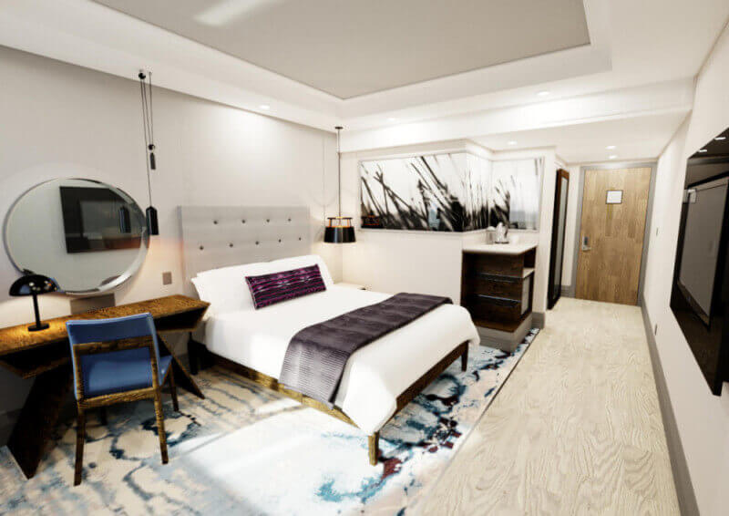 A hotel room with a wood dresser that has a matte finish on it.