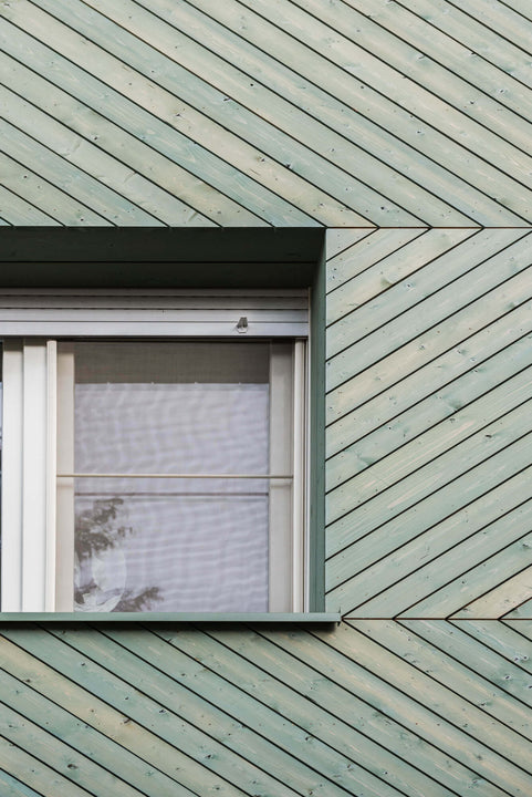 A closer view of chevron wood siding finished with a green exterior wood finish.