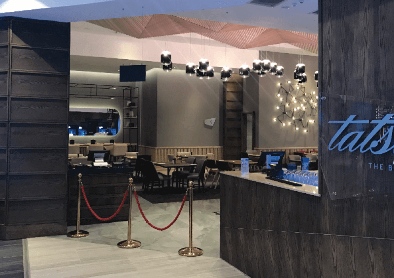 The entrance to a restaurant in a mall is made from wood panels that are finished with a beautiful wood finish.