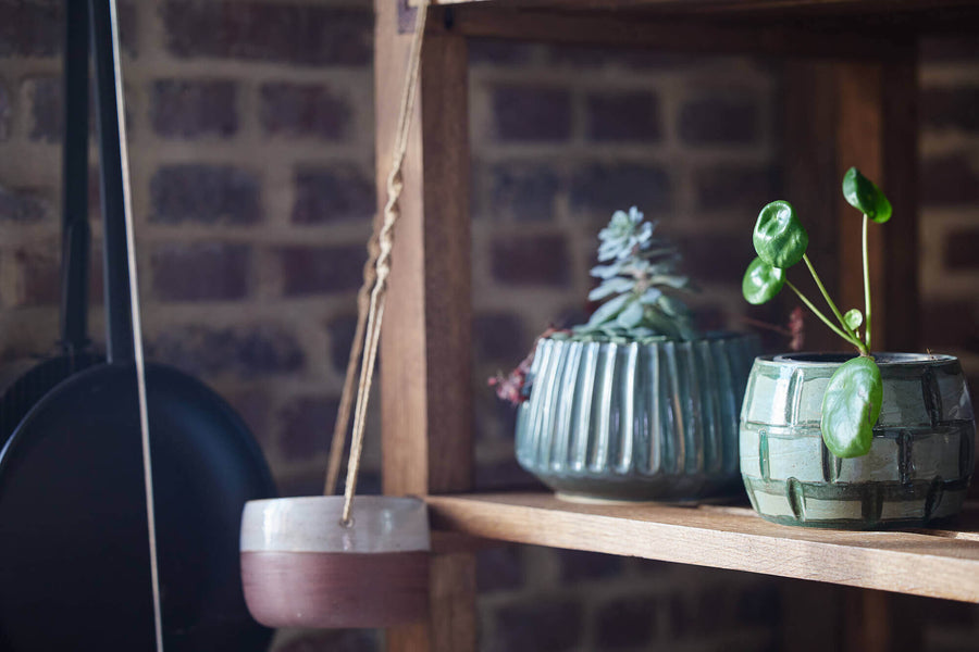 Rustic wood shelving with hand-made ceramic pots on it.