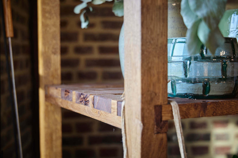 Rustic wood shelving featuring traditional wood joinery using hand tools, with a ceramic pot sitting on it.