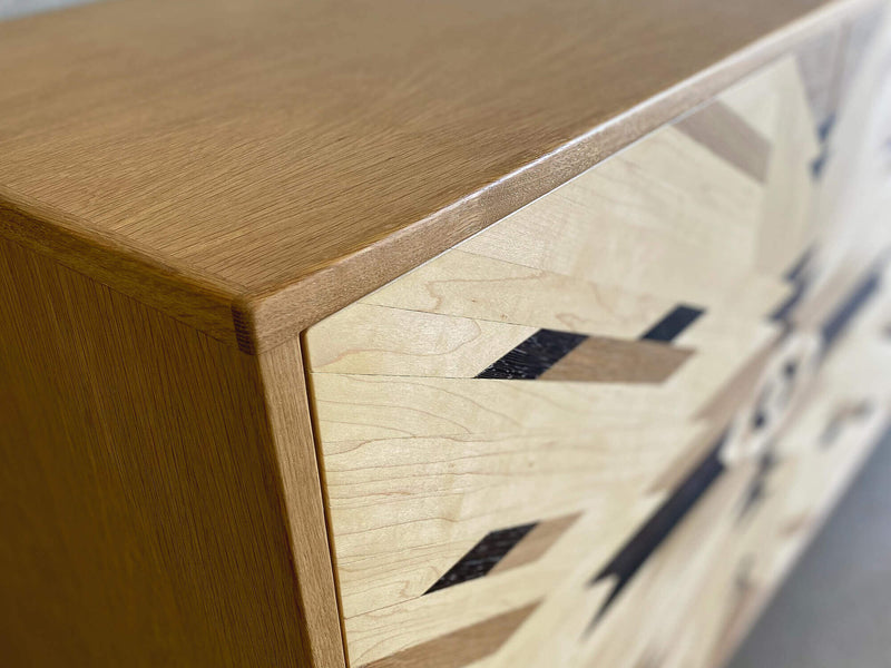 Corner details of a custom credenza with tribal pattern cabinet doors, made from solid maple, white oak, and wenge.