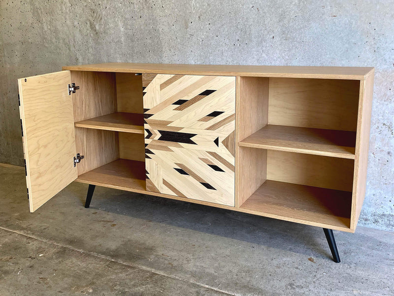A custom credenza with tribal pattern cabinet doors, made from solid maple, white oak, and wenge with a cabinet door open.