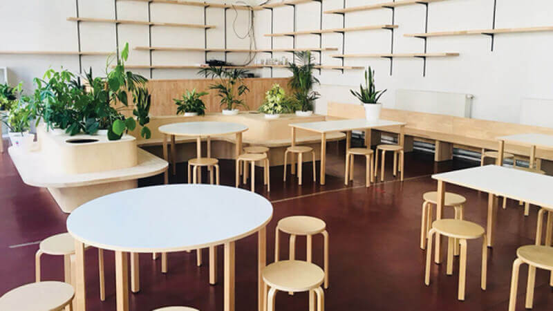 Tables and chairs in a school with a toy-friendly environmental wood finish on them.