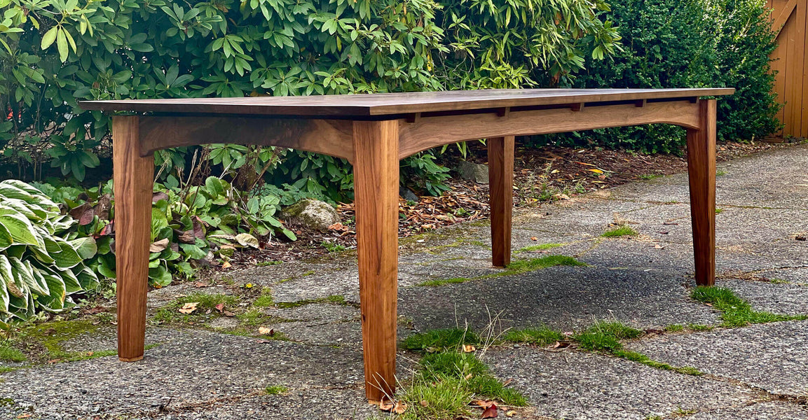 A solid walnut dining table with a wood oil finish.