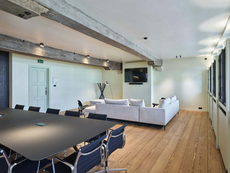 Conference room with conference table and couches and hardwood flooring.