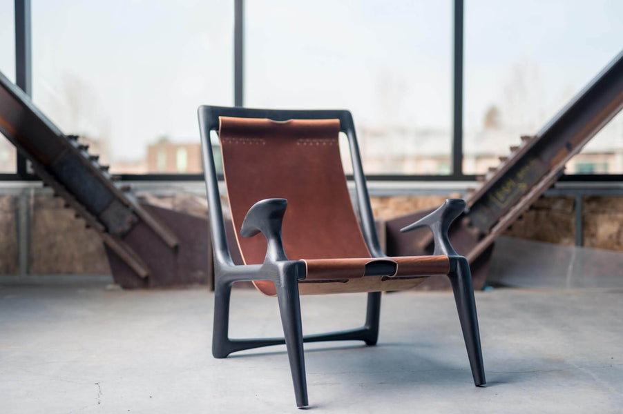 Custom wood chair with leather back sitting in a warehouse with large windows.
