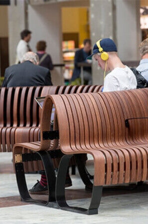 A student sitting on a wooden public bench.
