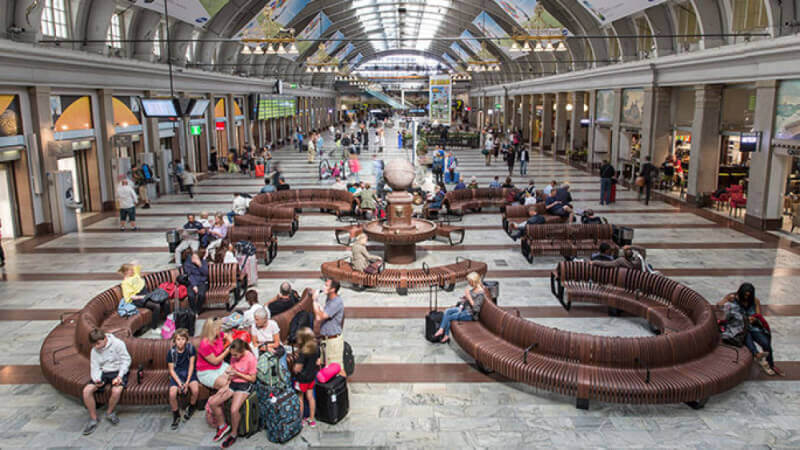 An overview of Stockholm Central Station waiting area that contains multiple wooden benches in curved patterns.