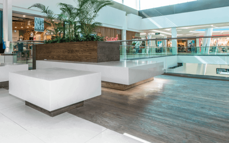 Wooden planter boxes and seating in a mall are finished with a matte wood finish.