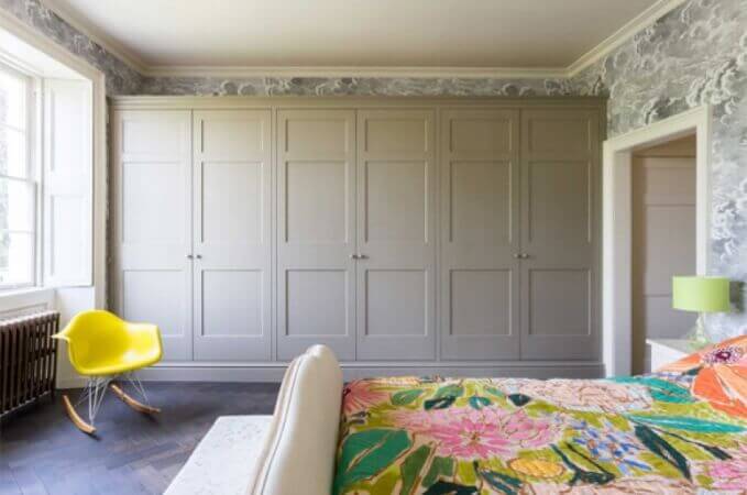 A bedroom with white wall cabinets and a herringbone hardwood floor.