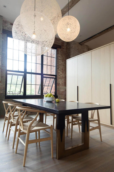 New York loft with circular lights above dining table in a room with hardwood flooring.