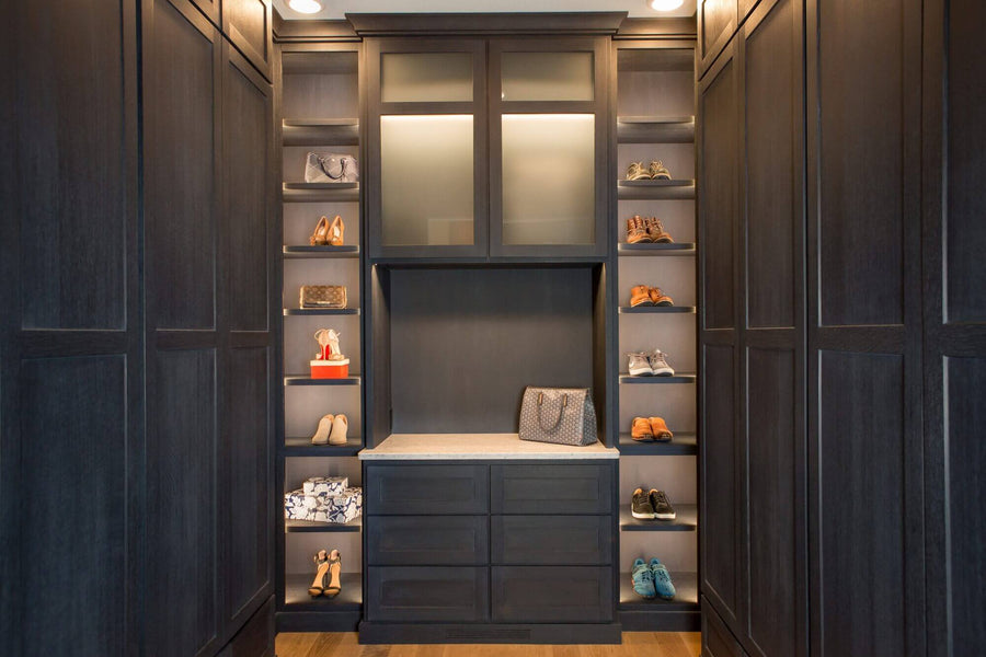 Luxury closet with shoe shelving and dark cabinetry.