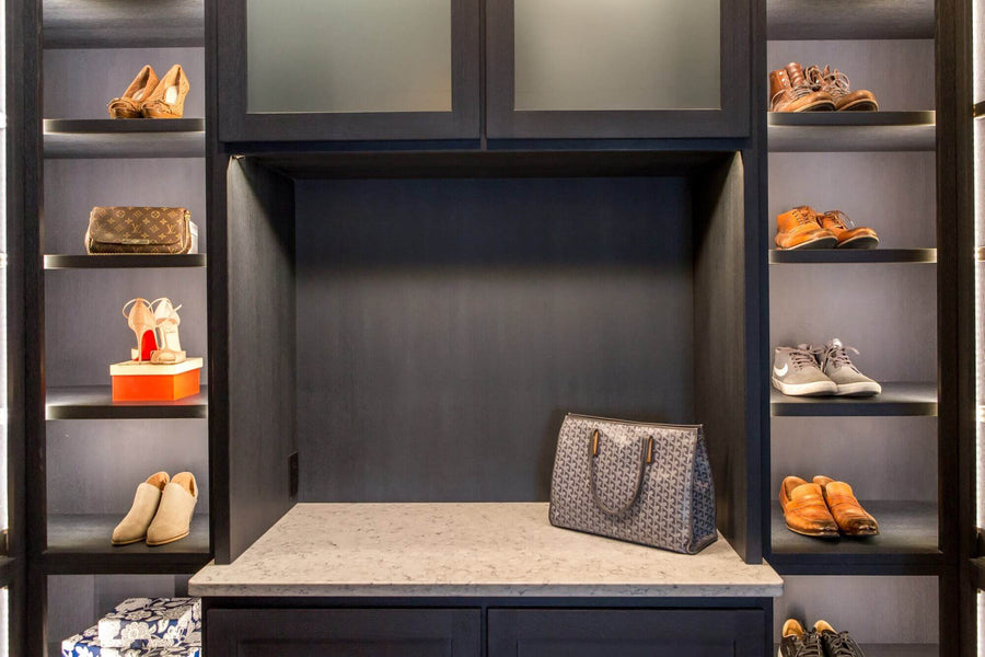 Lighted shoe shelving and accessory counter in a luxury closet.