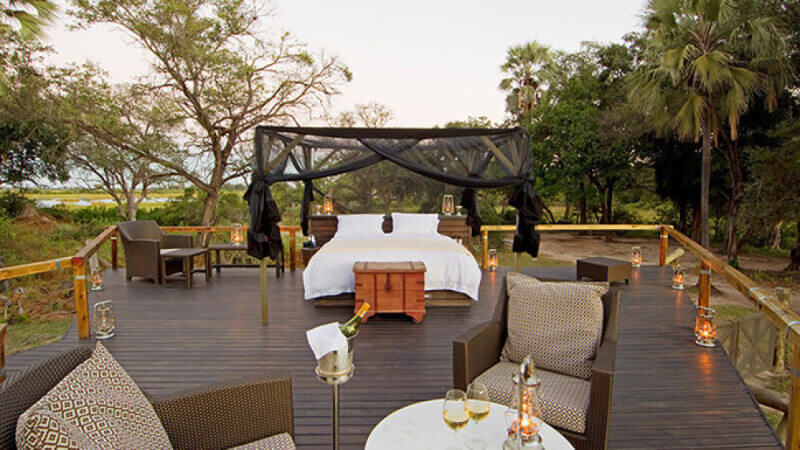 An outdoor patio with wood decking and a bed on it makes a cozy evening.